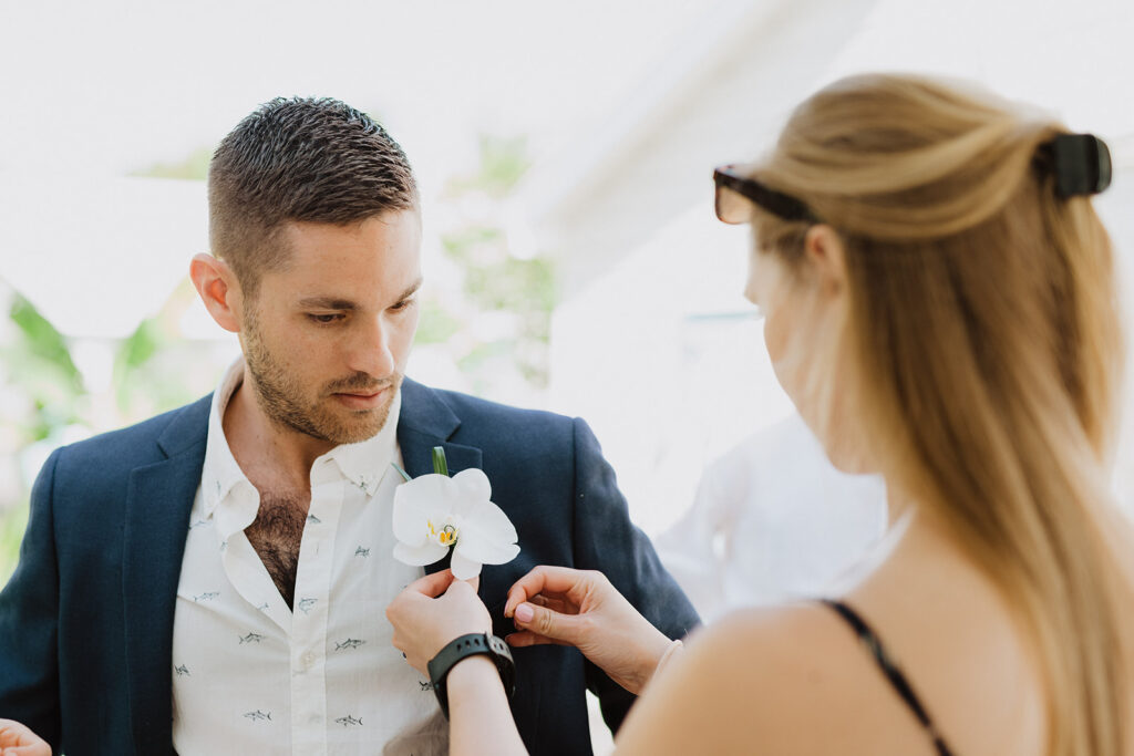 Virginia Based Wedding planner Blue Sapphire Events pins a boutonniere on a groom - displaying one of the many reasons why you should hire a wedding planner.