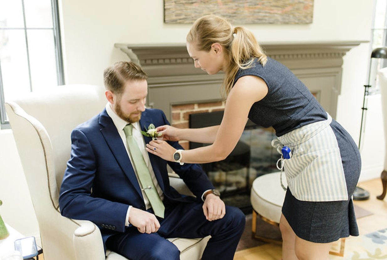 Washington DC Wedding Planner Kolena of Blue Sapphire Events pins a boutonnière on a groom before the wedding ceremony.